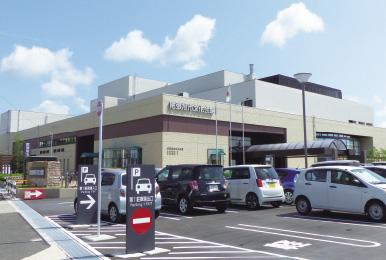 写真：尾張旭市文化会館様の外観。駐車場に沢山の車が停まっている。