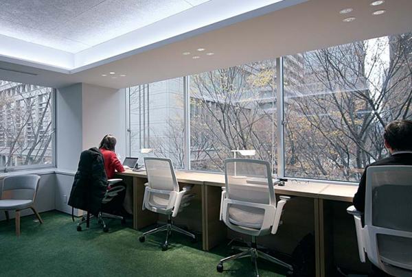 写真：窓際に設置された机と椅子で作業をする人たち。