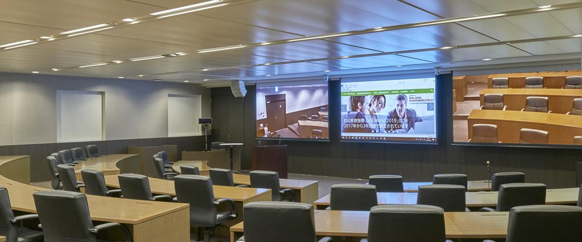 写真：第一三共株式会社様の多目的型交流施設『NEXUS HAYAMA』内のセミナールーム。壁面には三台の大型スクリーンを設置。