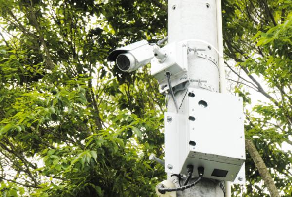 写真：電柱上部に設置されたた防犯カメラシステムとネットワークカメラ用60 GHz通信BOX。