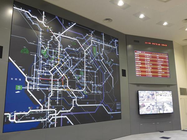 写真：管制センターに設置された2基のマルチビジョンシステム。中央に配置された画面には、熊本県内全域の交通状況を表示。写真右上の画面には渋滞情報などを一覧表示している