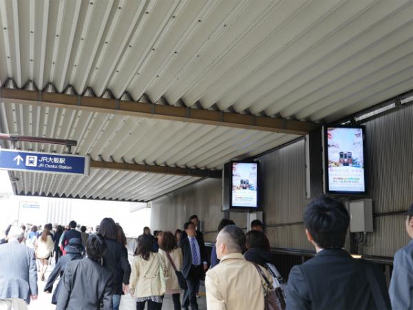 写真：JR大阪駅との連絡口。多数の人がサイネージに目を向けている