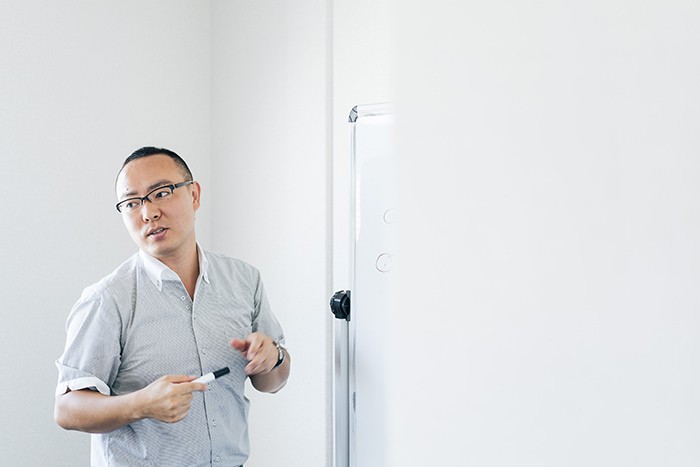 Terminal Qについて、白板に図を描きながら説明する名取氏