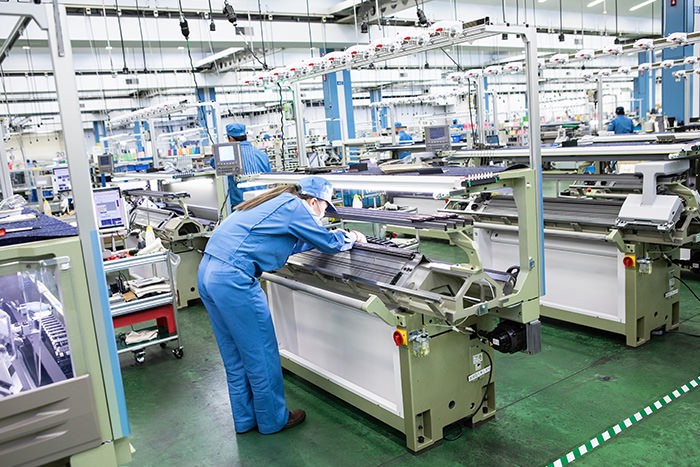 コンピューター横編み機を製造する作業員