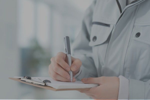 紙の台帳に記入する男性の手元