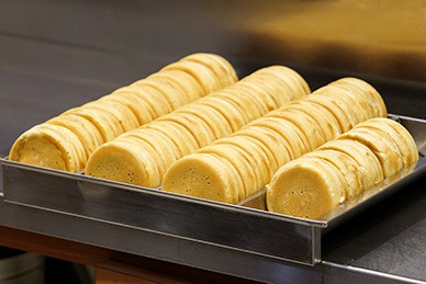 御座候様では、⽣地の製造から焼き上げまでを各店舗で⾏い、できたての商品をその場でお客様に提供。