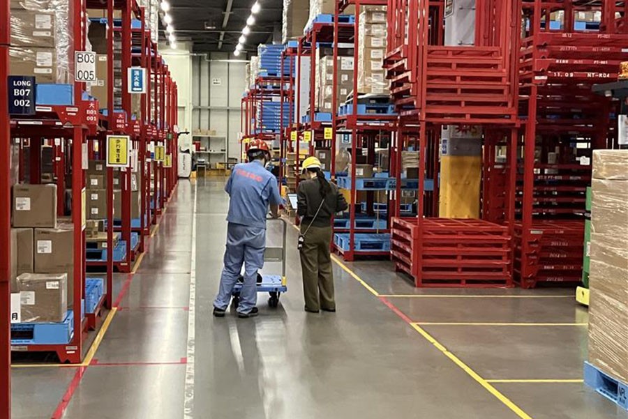 倉庫内で現場担当者と対話する古屋