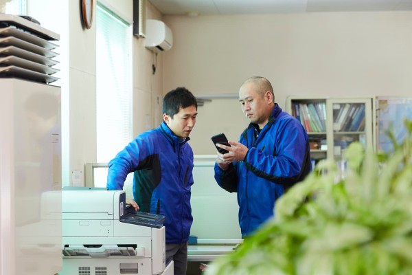 オフィスでスマホを見ながら相談する2人