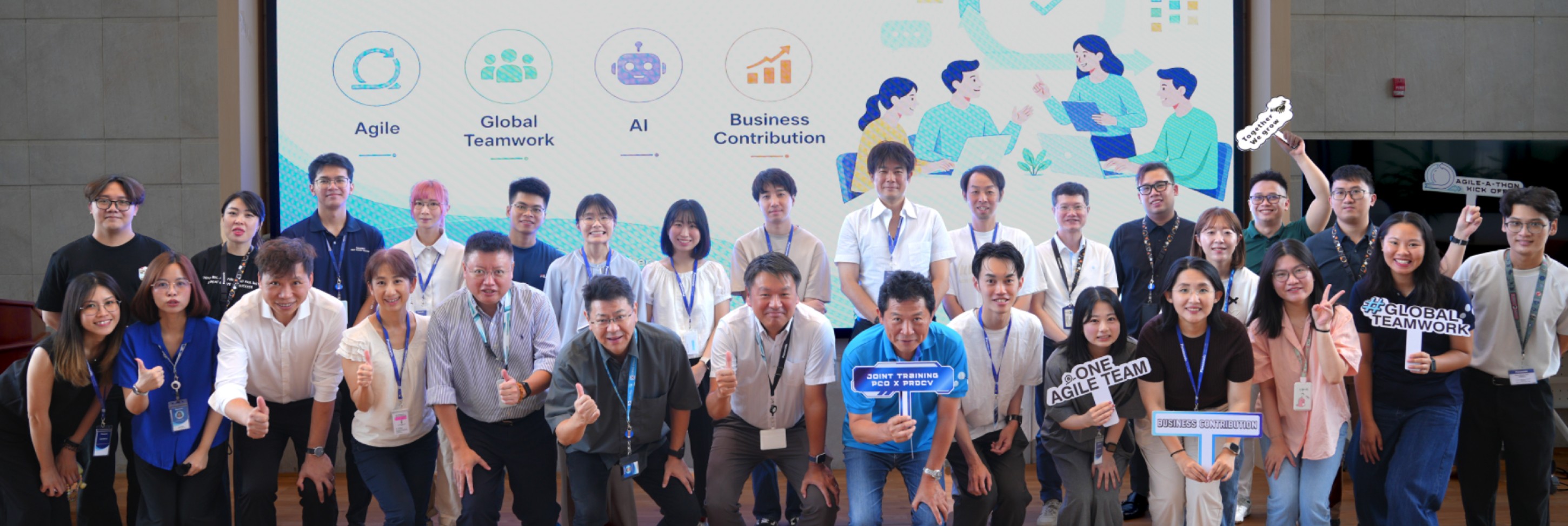 「Agile」「Global Teamwork」「AI」「Business Contribution」の4つのテーマが映し出されたスクリーンの前で、笑顔で集合写真を撮るチームメンバーたち