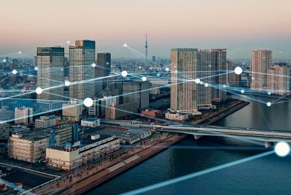 都市の夕景、ビルの上にネットワークを示す線と光の点が配置されたグラフィック。