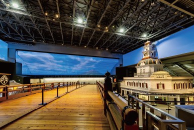 屋内に再現された木製の橋と建物、背景には夜空のスクリーン。