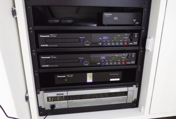 写真：AV操作卓に設置された映像コミュニケーションユニット、ＢＤレコーダ、ライブカメラ用ネットワークレコーダー。