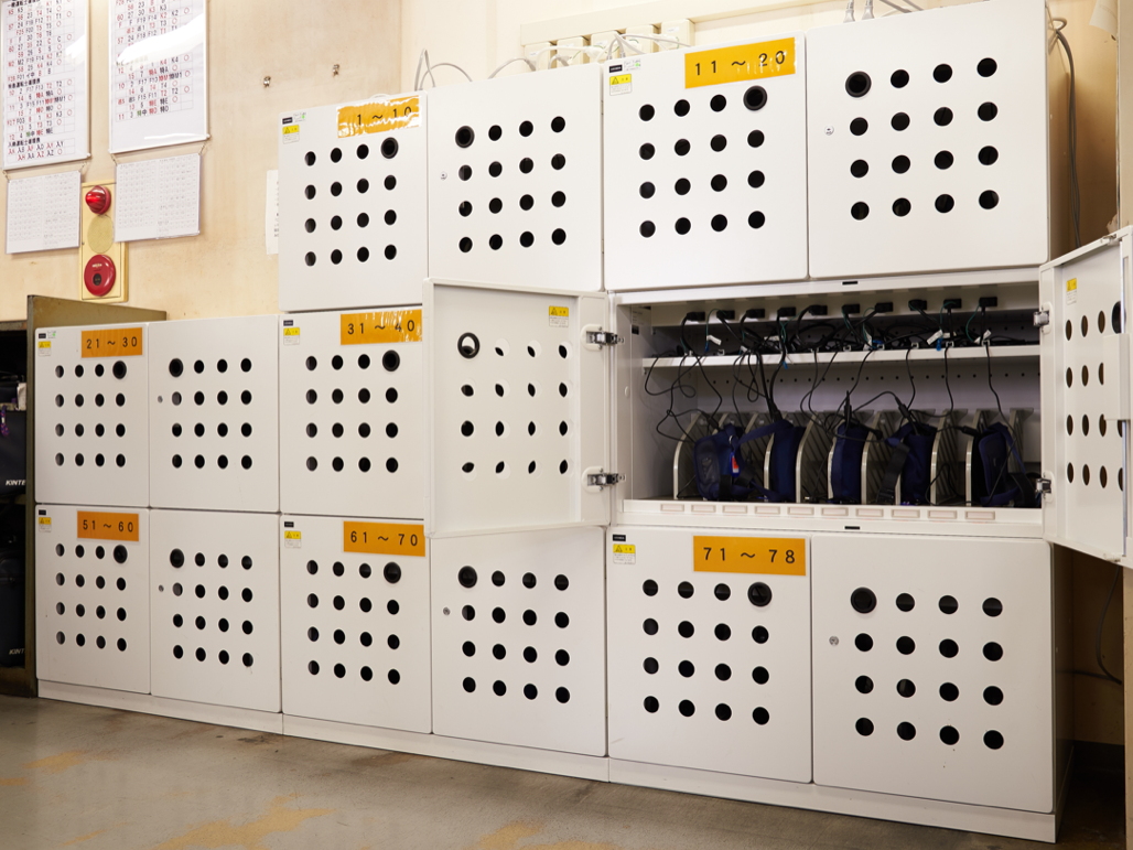 写真:効率的に運用ができるよう事務所には約80台が収納できる充電ラックを設置