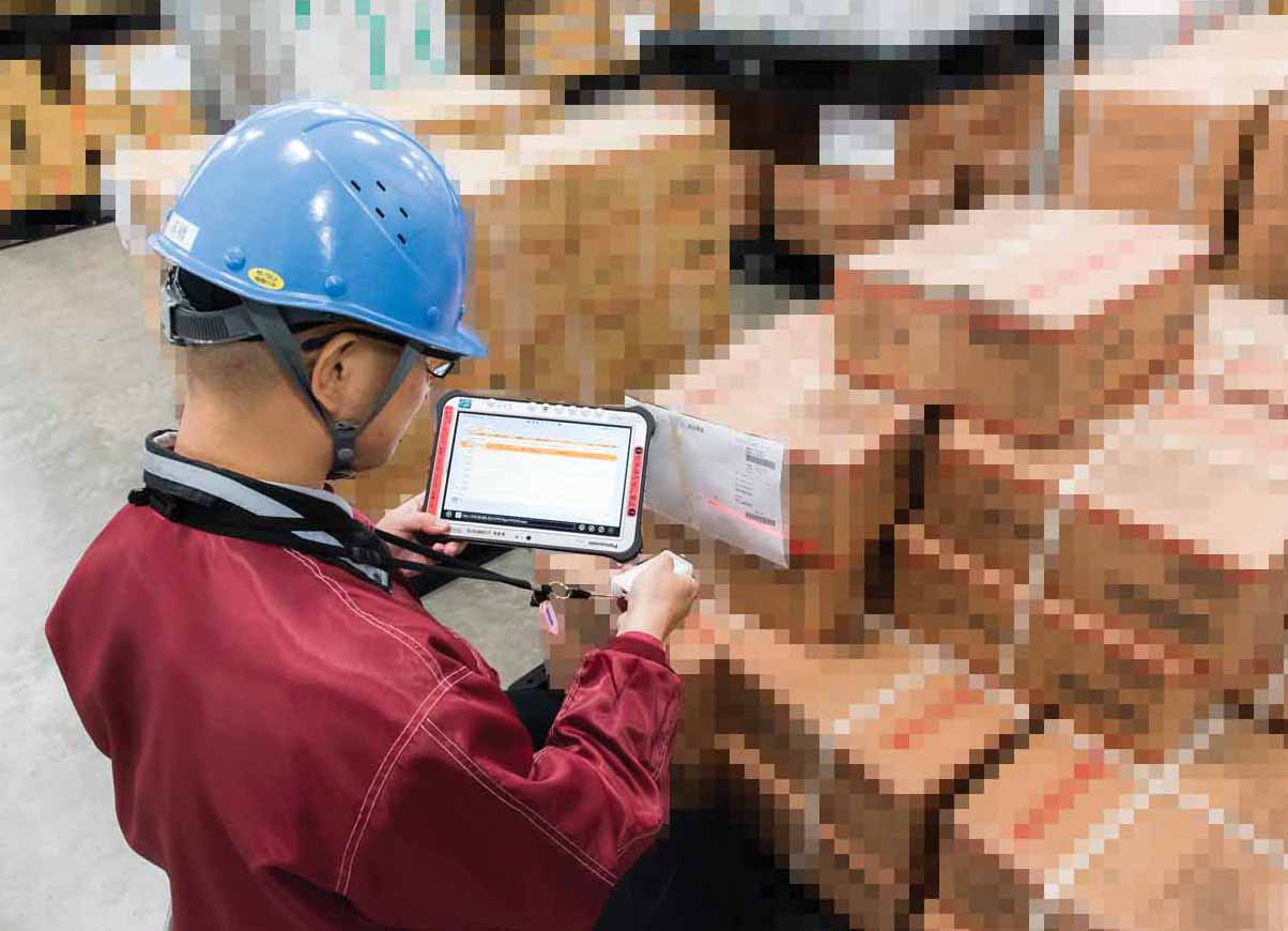 写真：荷札のバーコードをリーダーでスキャンすると、Bluetooth経由でTOUGHPADに情報が送られ、システムで照会された伝票情報が画面に表示されます。