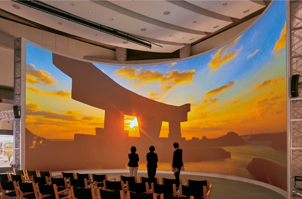 写真：高さ7 m×幅18 ｍの巨大な半円形のスクリーンに、海の正倉院といわれる沖ノ島の臨場感ある映像が常時映し出されている