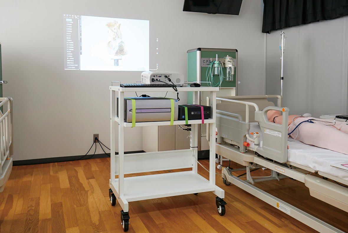 写真：医療用台車にセッティングされた多視点3D解剖教育システ ムとプロジェクター