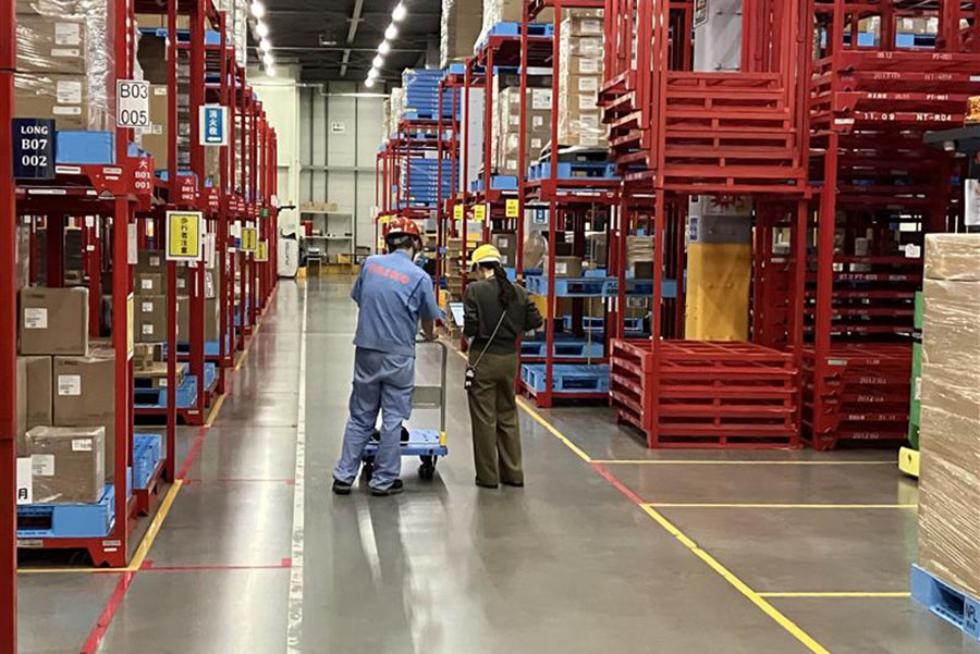 倉庫内で現場担当者と対話する古屋