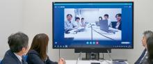 写真:液晶ディスプレイに映った人々とビデオ会議をしている様子。